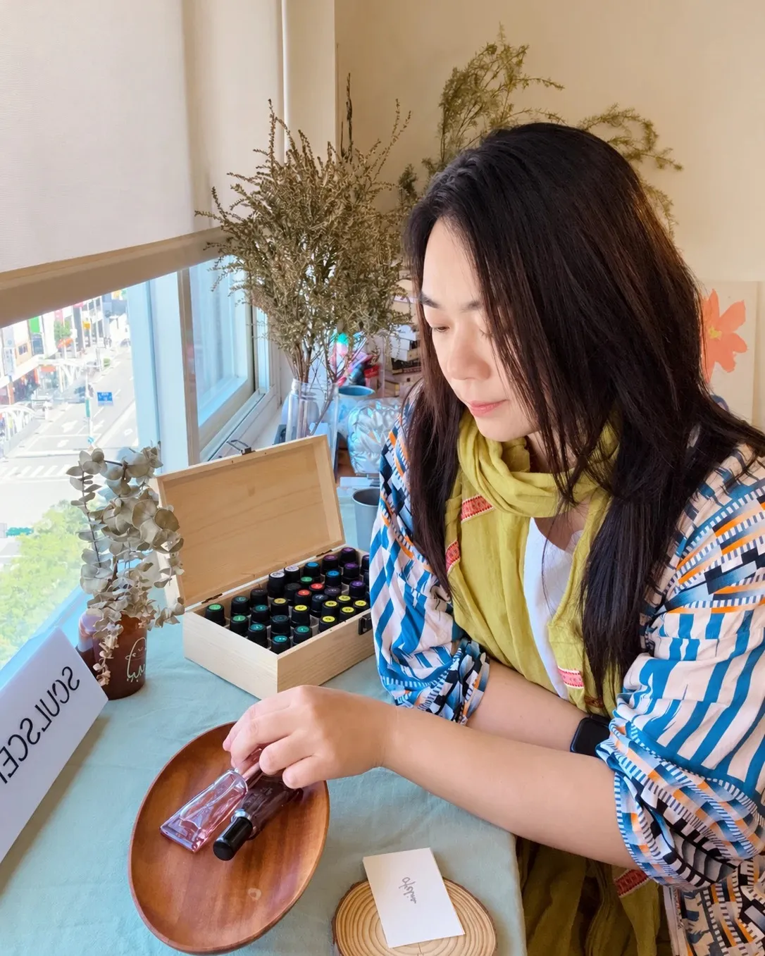 香氣策展人陳怡君，在窗邊的調香桌前挑選精油